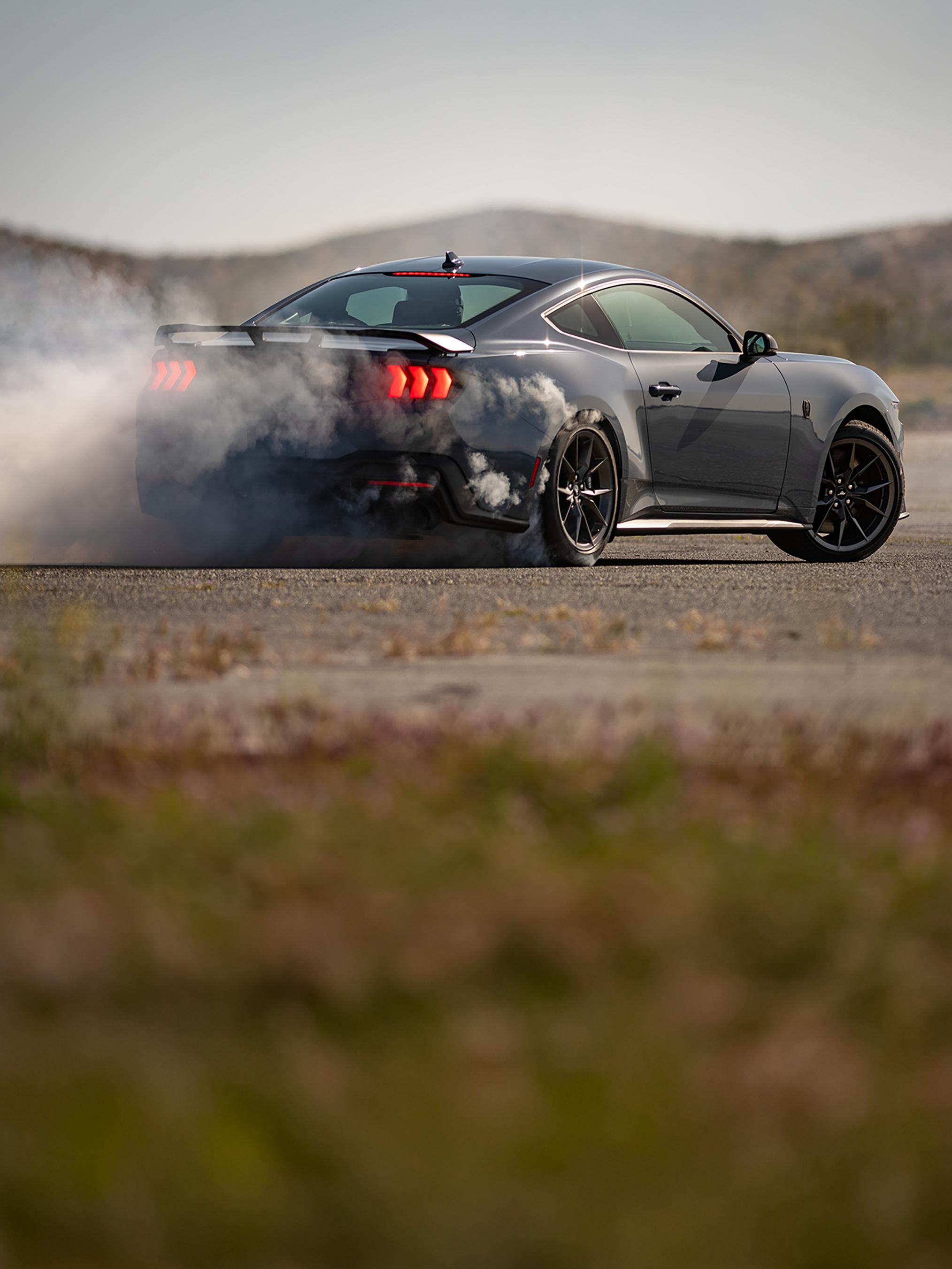 2026 Ford Mustang® Dark Horse® Fastback in Vapor Blue Metallic with a driver performing burnouts on a closed course