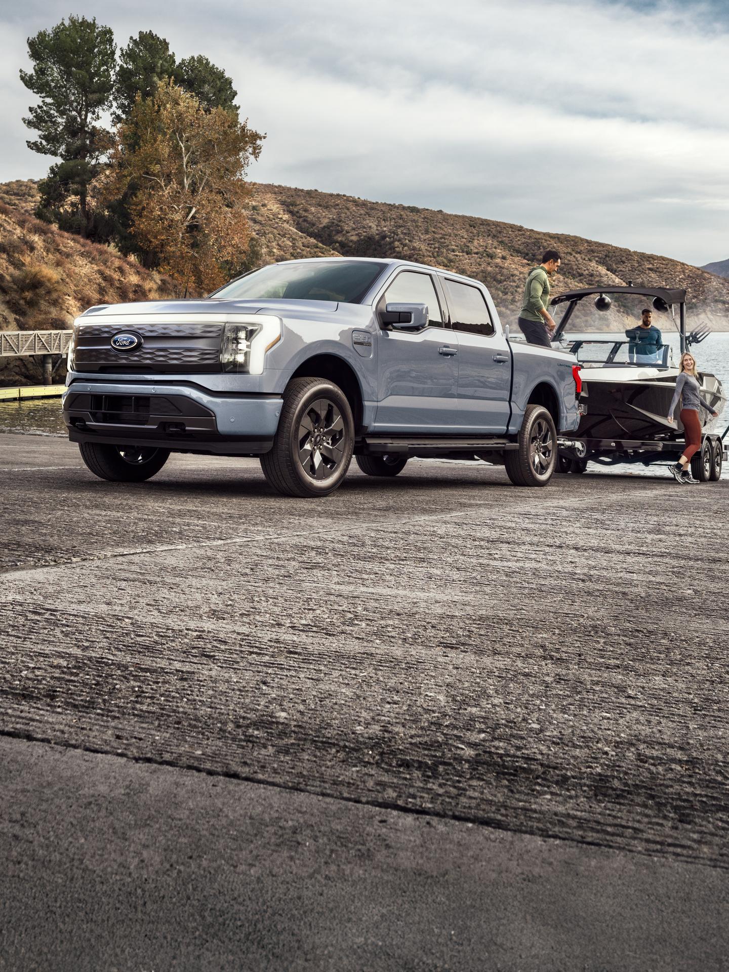 An F-150 Lightning parked at a shore with a boat hitched.