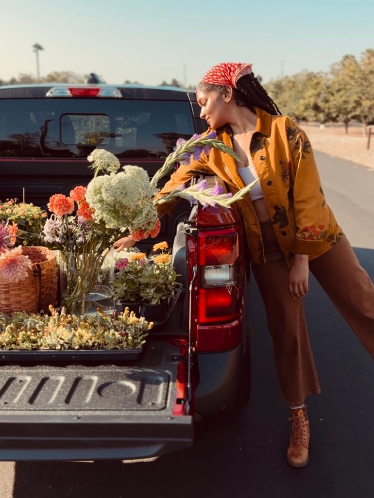 Person reaching for flowers loaded into the bed of a Ford pickup truck.
