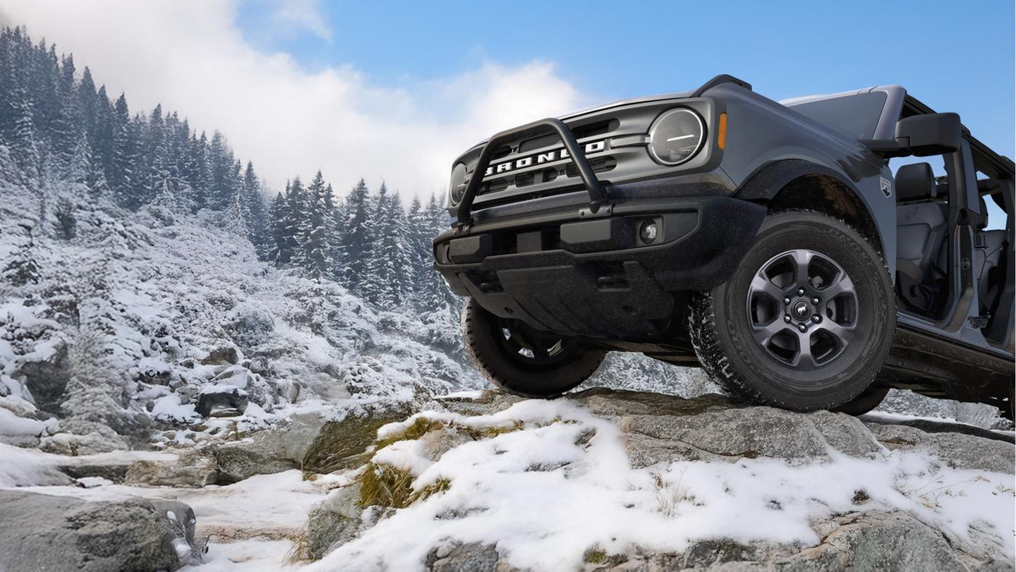 Front half of a 2025 Bronco with doors off parked on a snowy mountain.