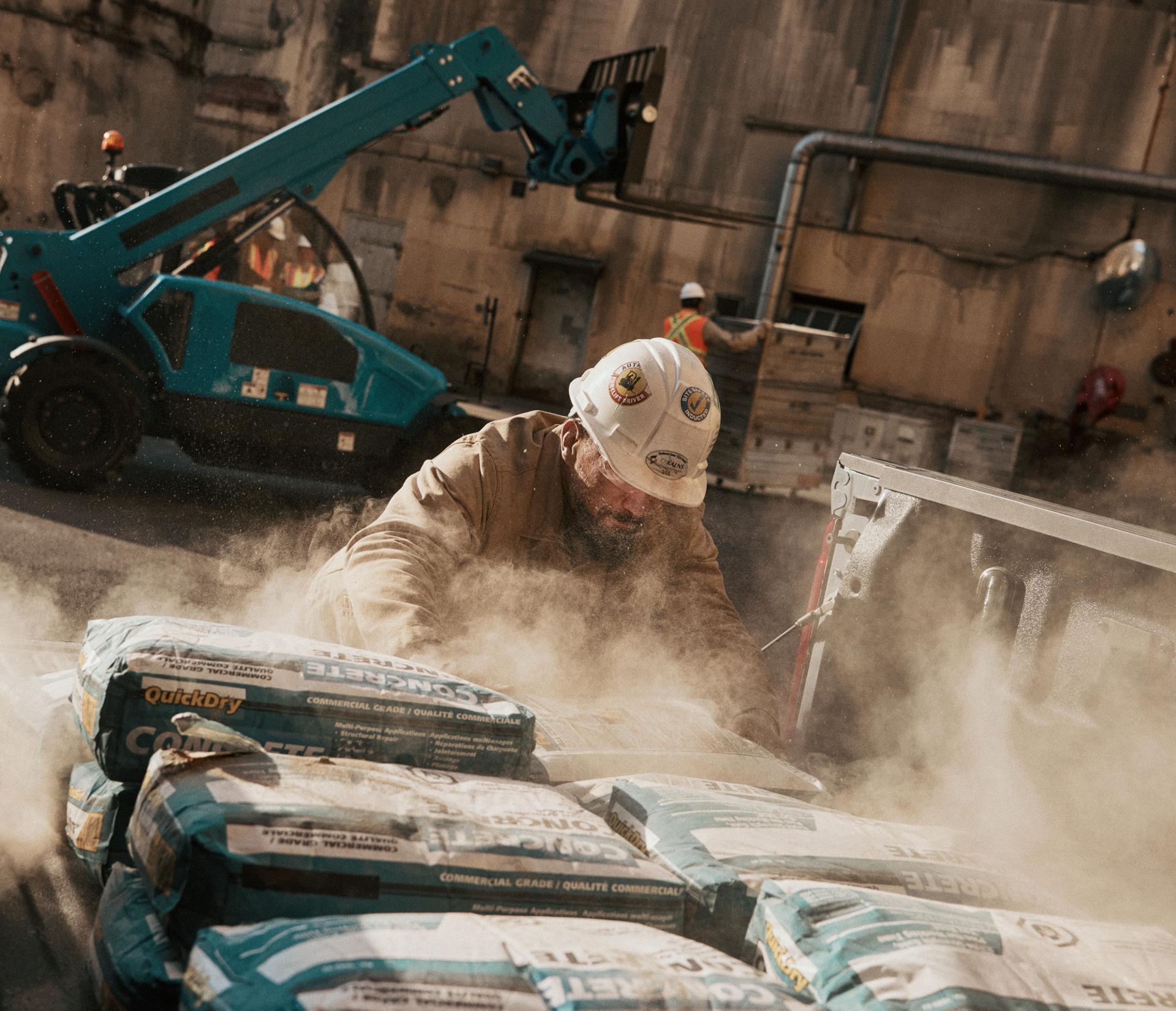 A construction worker unloads materials from the bed of a Ford Super Duty at a job site.