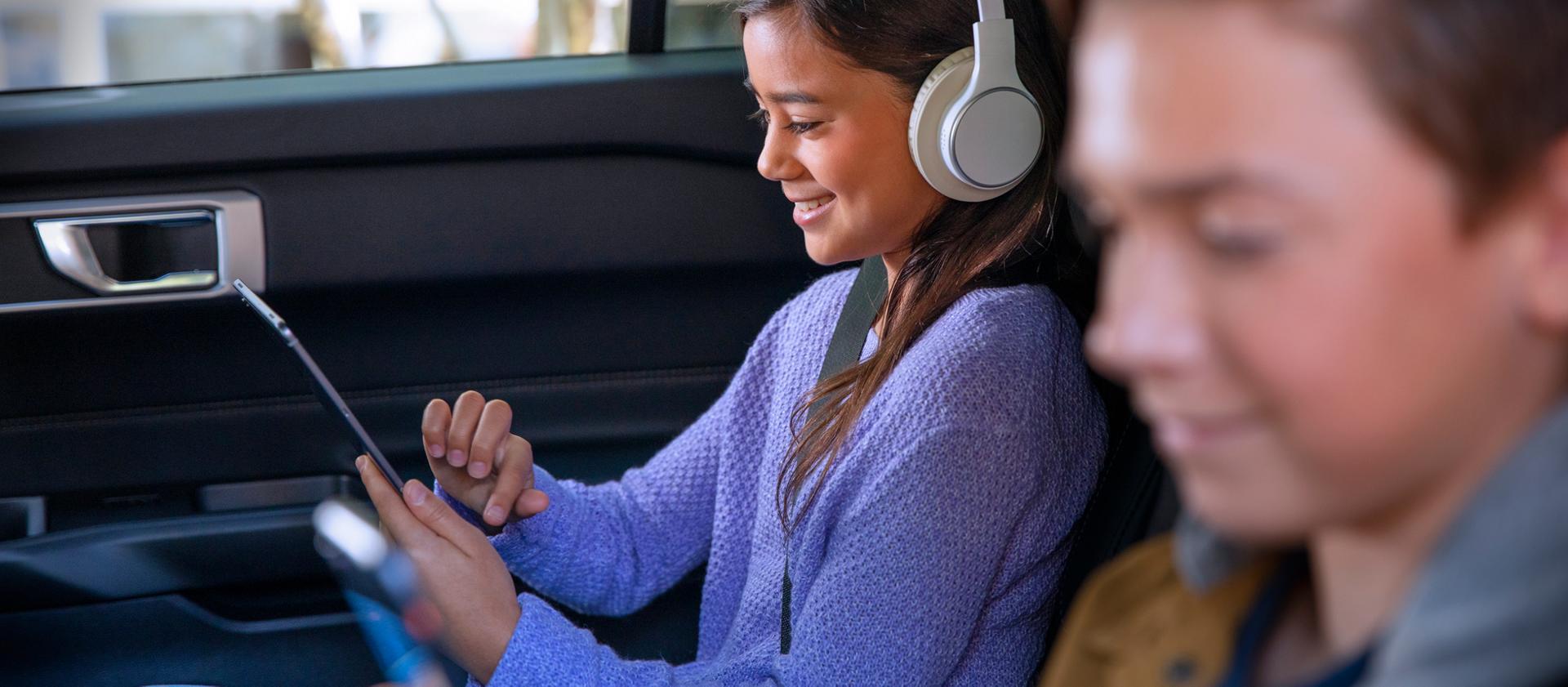 Children using mobile devices in the back seat of a vehicle