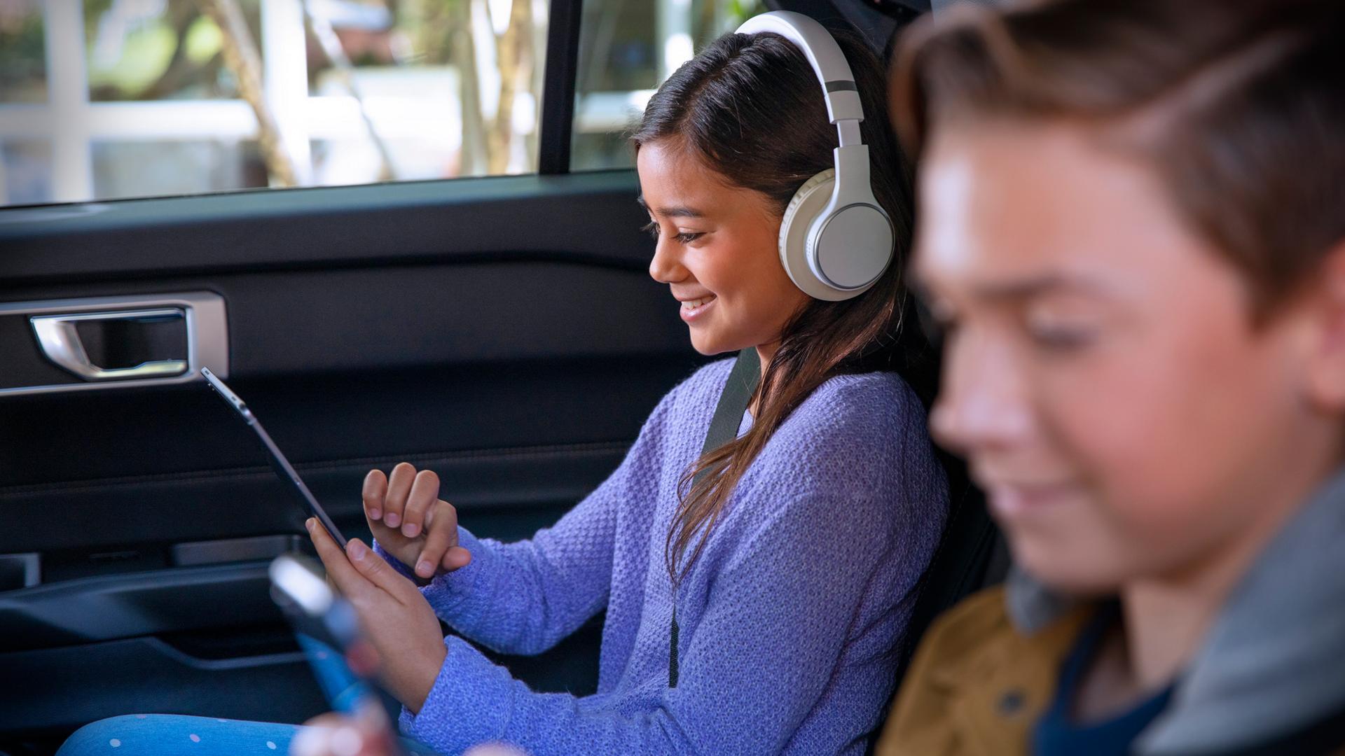 Children using mobile devices in the back seat of a vehicle