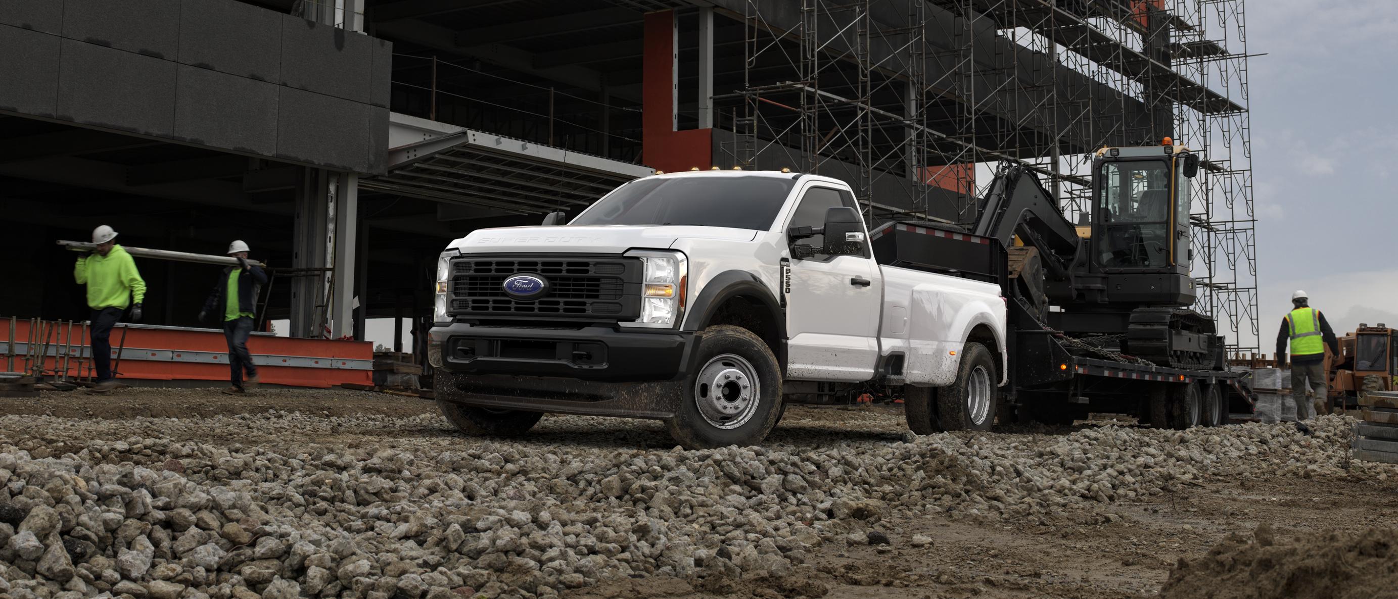 2026 Ford Super Duty® F-350® Lariat® model pulling a large flat-bed trailer with a heavy tractor on a construction site
