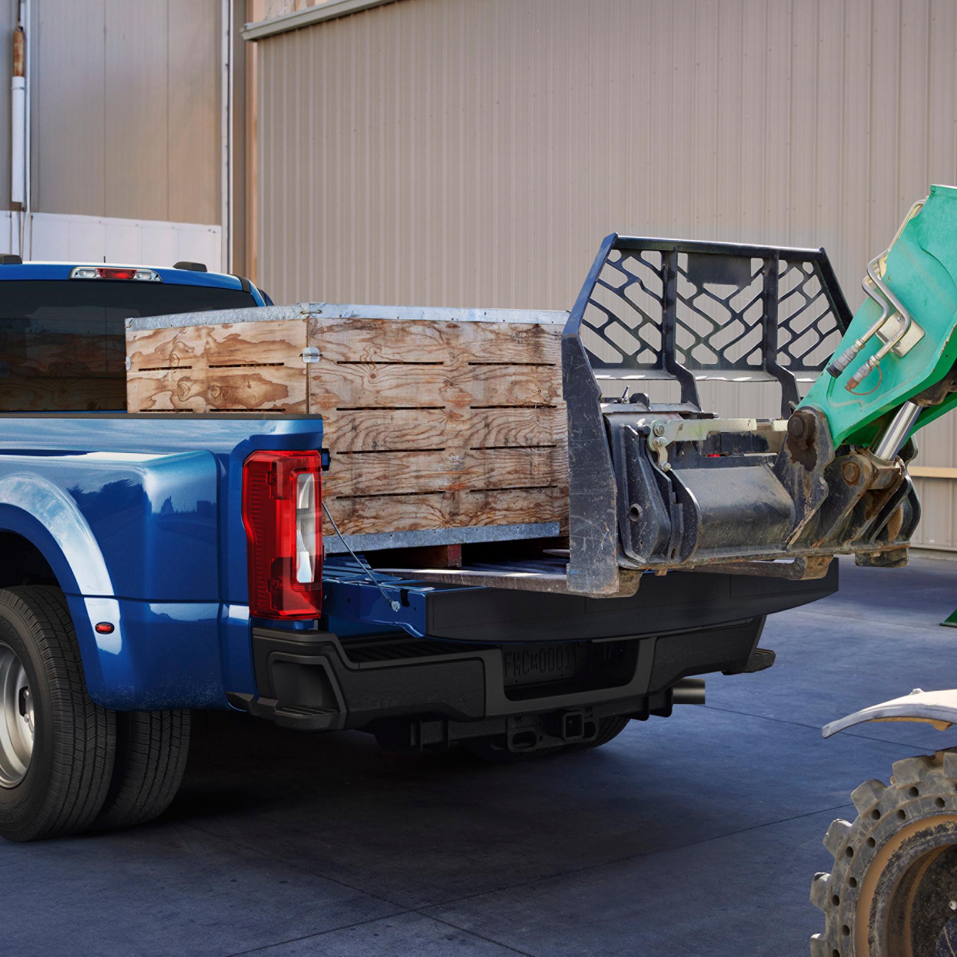 A 2027 Ford Super Duty® F-350® Lariat® model with a heavy crate being loaded into the truck bed