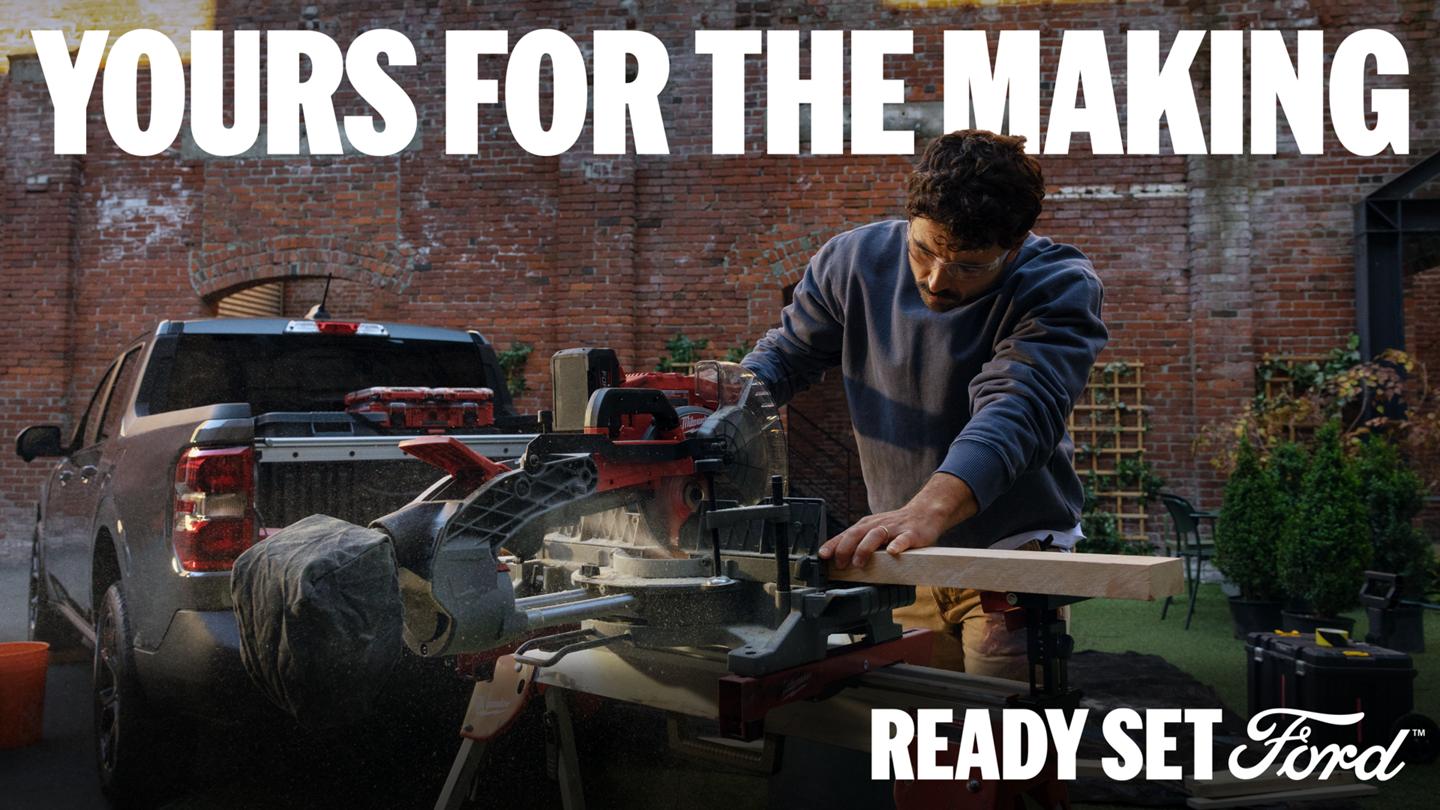 A man cuts wood with a power miter saw outdoors in front of a Carbonized Grey 2026 Ford Maverick truck, set against a brick building. Headline reads "YOURS FOR THE MAKING".
