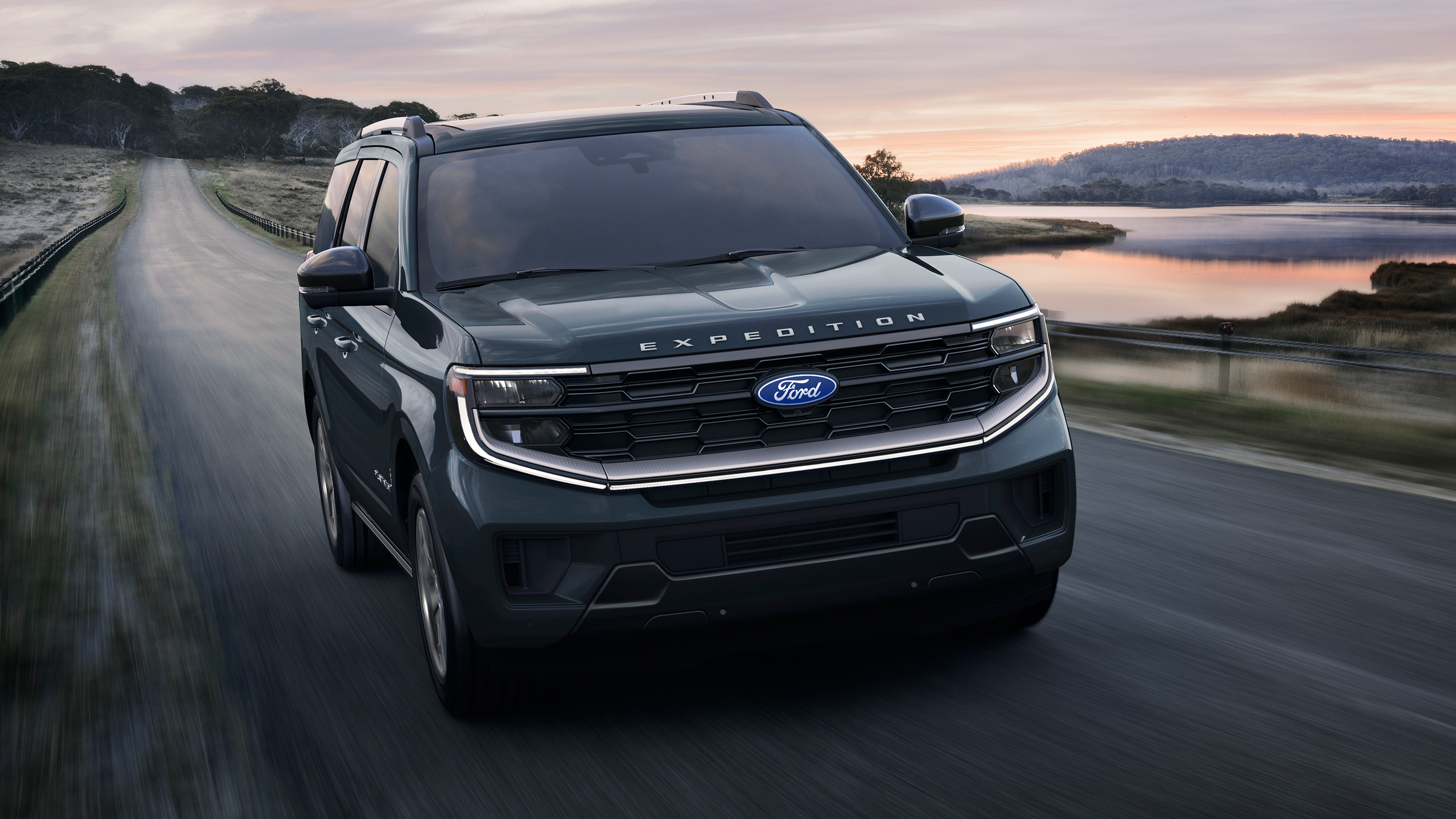 2027 Ford Expedition® Platinum™ SUV with available Platinum™ Ultimate Package being driven on a lakeside highway