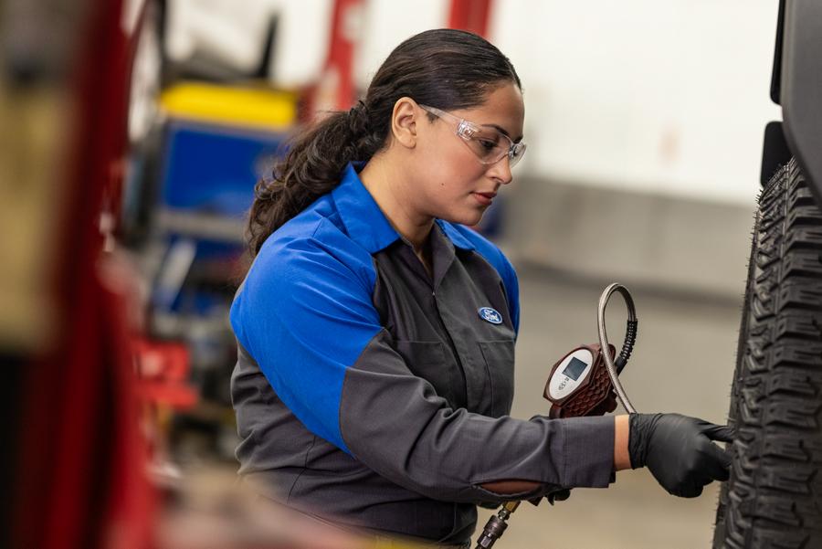 A Ford Service Technician works on a tire on a lifted vehicle.