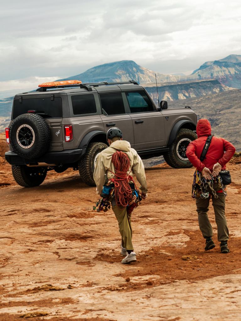 Two hikers approaching a 2026 Ford Bronco® SUV parked near a scenic overlook