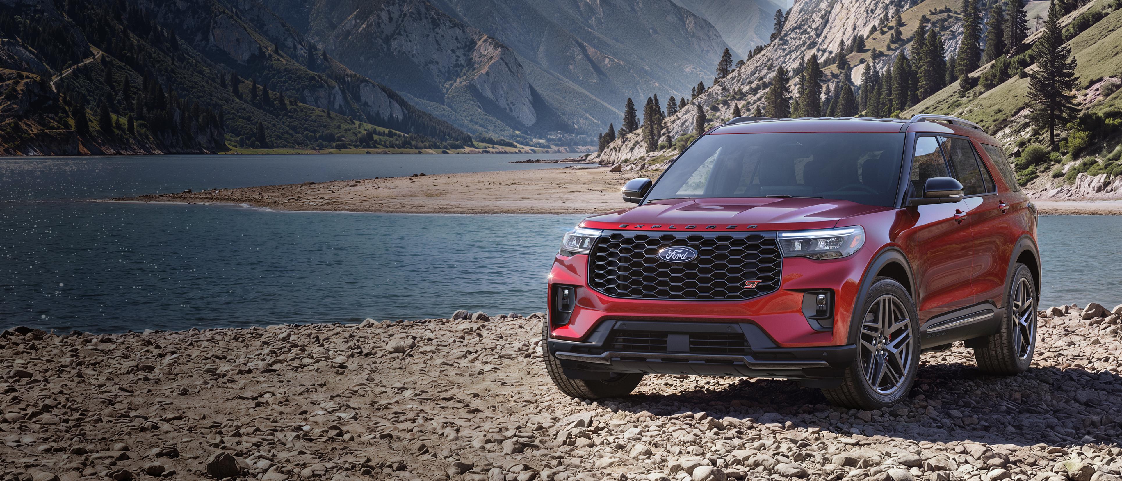 A 2027 Ford Explorer® ST model parked on a rocky expanse near a mountain lake
