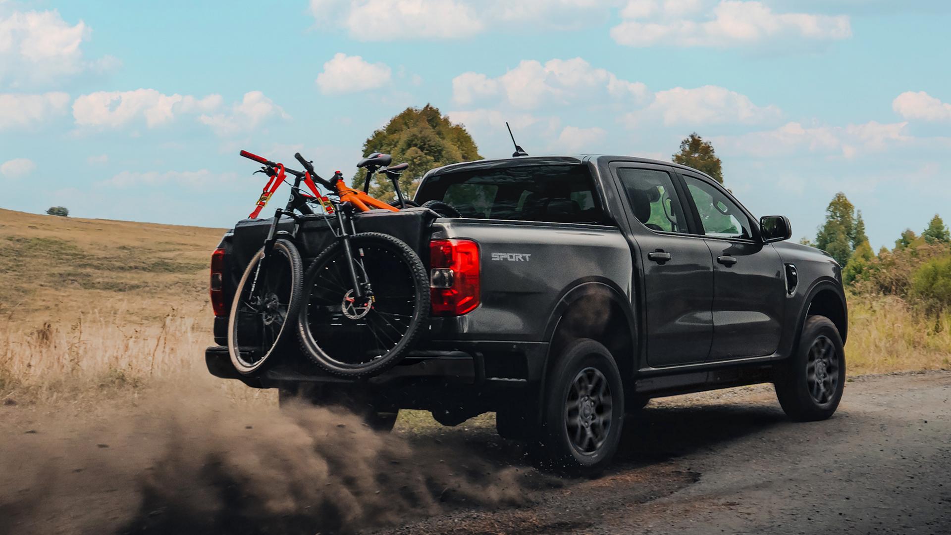 A 2026 Ford Ranger® truck being driven on a dirt road with multiple bikes in the bed