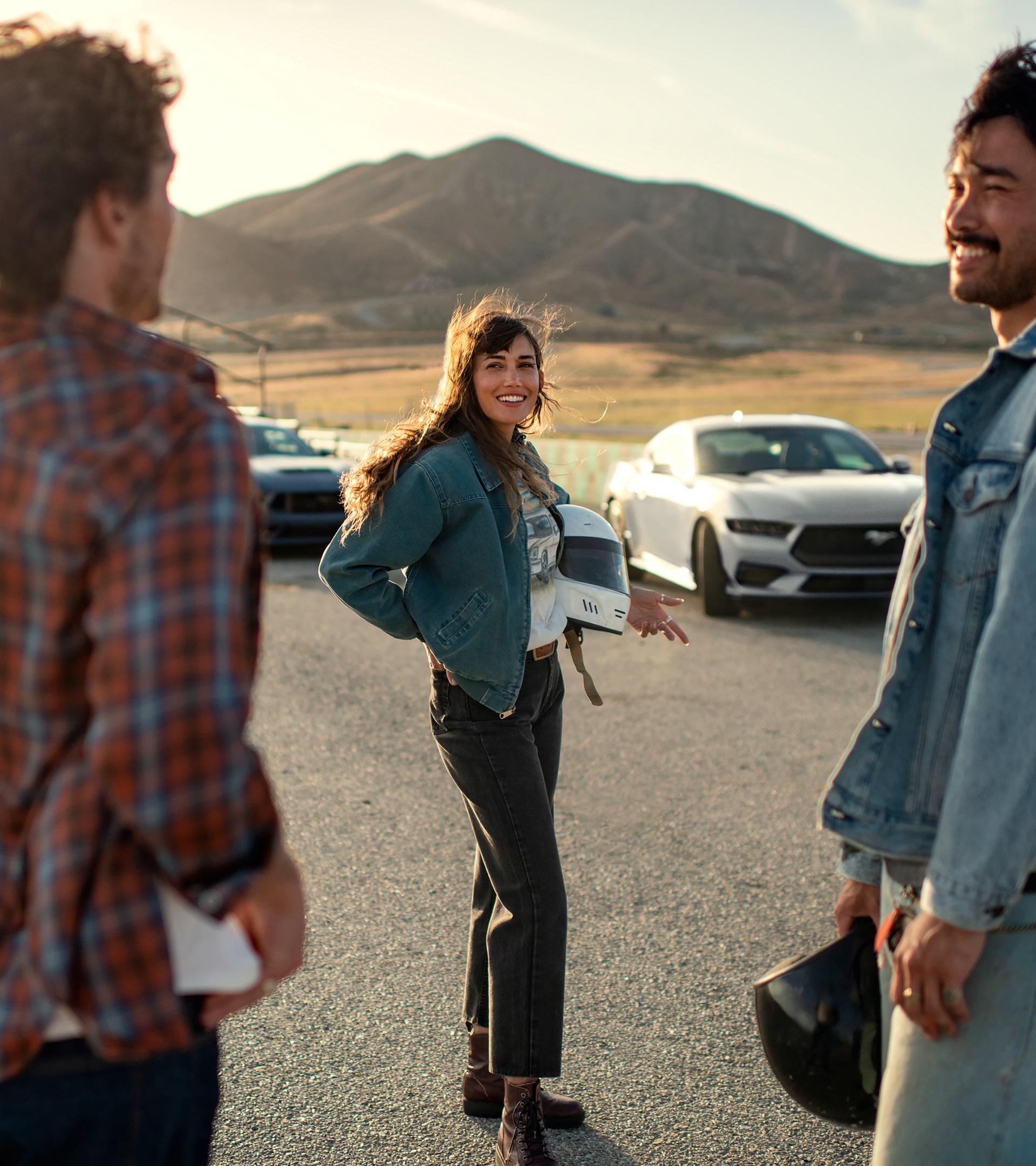 A 2026 Ford Mustang® fastback parked near a racecourse with two people nearby