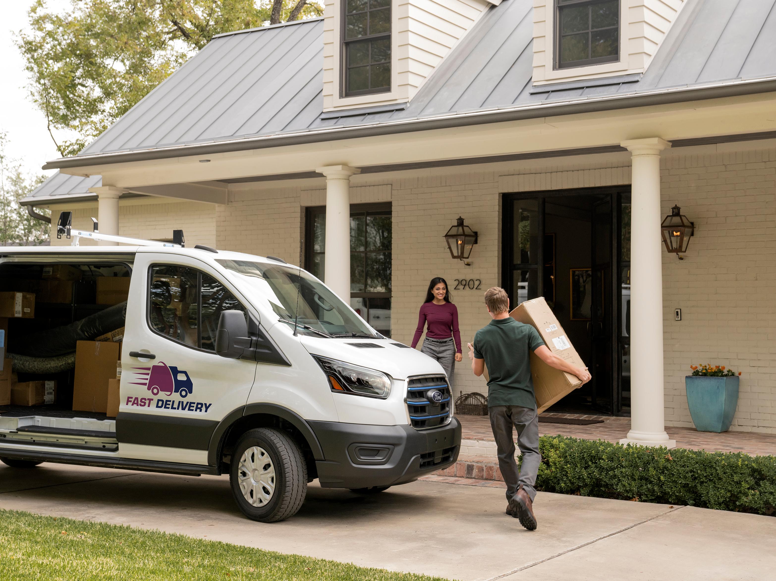 A White 2027 Ford Transit® Van, man carrying package to woman at house