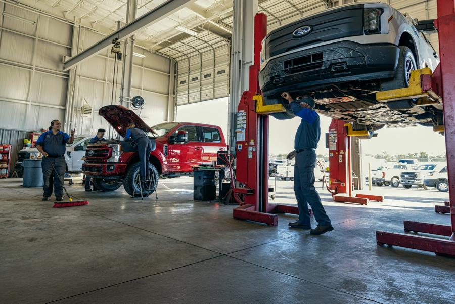 Mechanics working on vehicles in a repair shop.