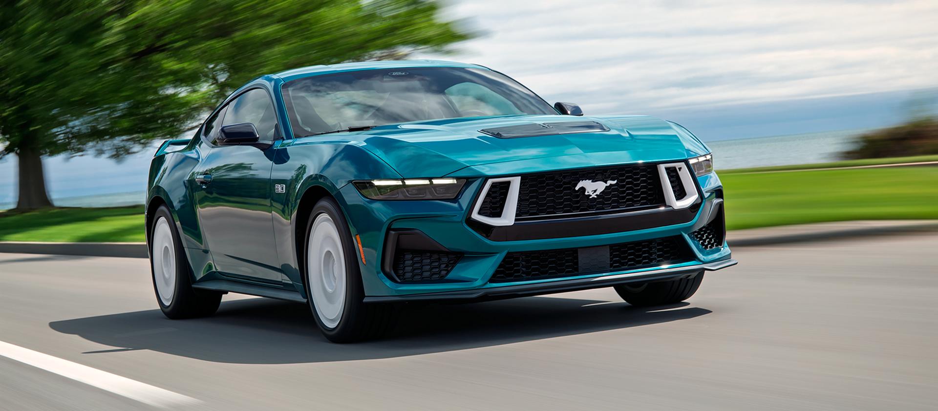 A 2026 Ford Mustang® GT Premium with the available Mustang FX® Package being driven near a lake