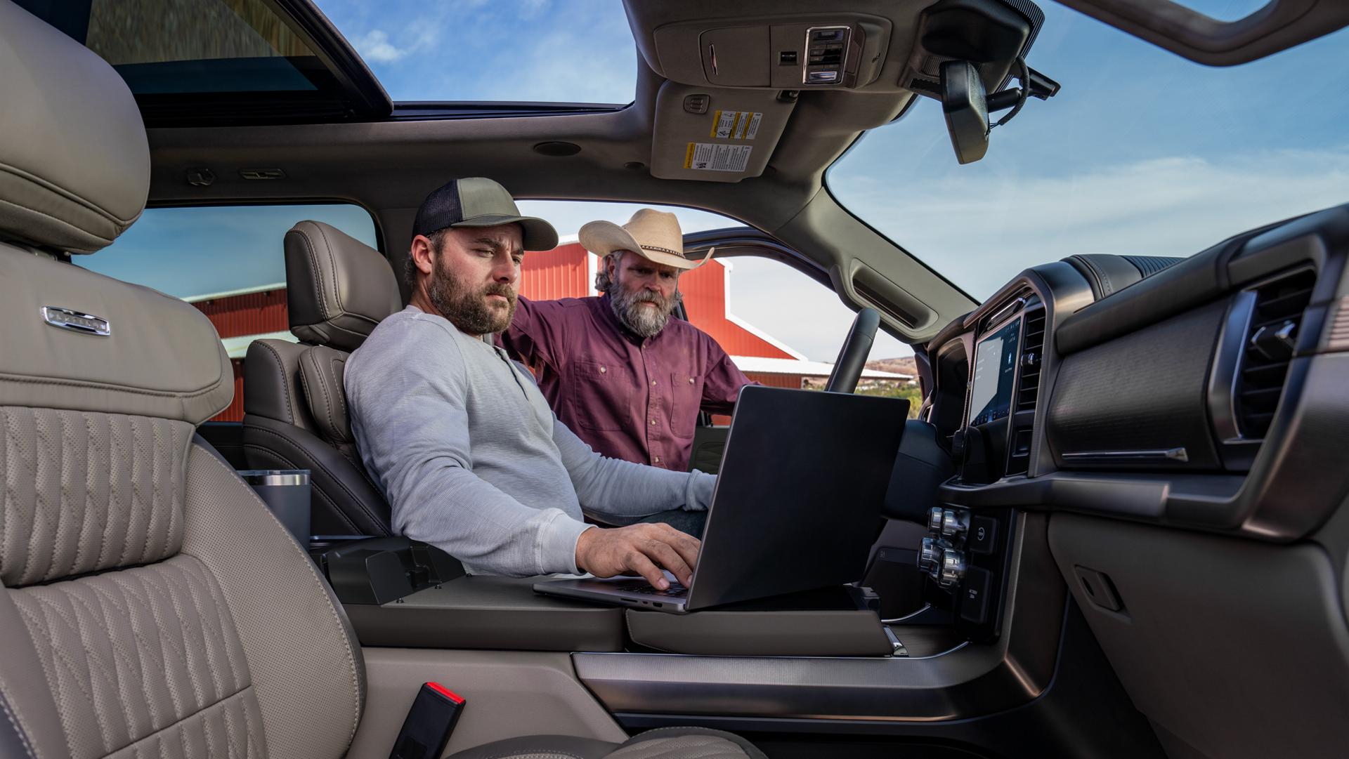Two men looking at a laptop computer on the Interior Work Surface of a 2026 Ford F-150 Platinum® model