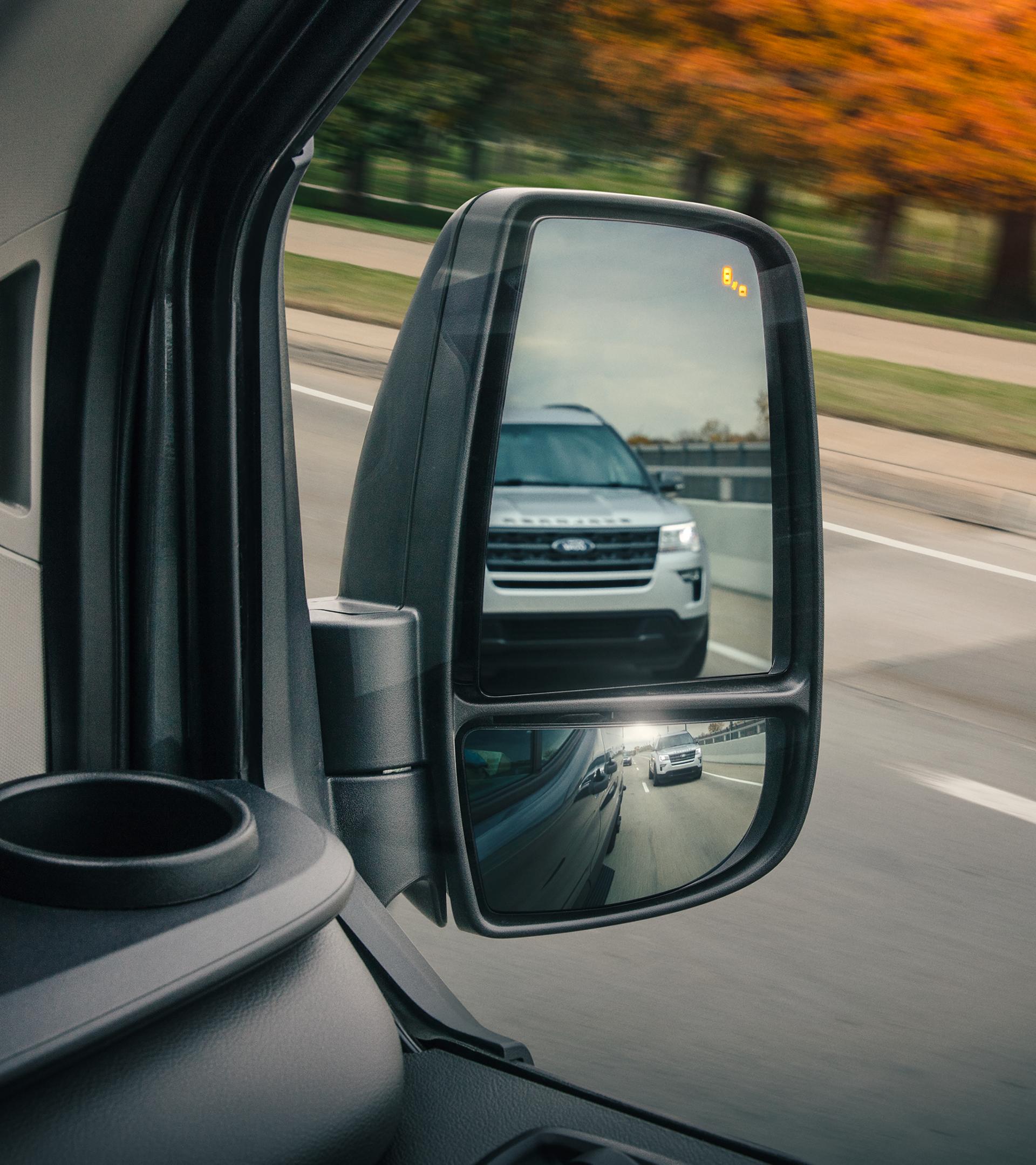 Close-up of side view mirror on a 2025 Ford Transit® Van showing vehicle blind spot