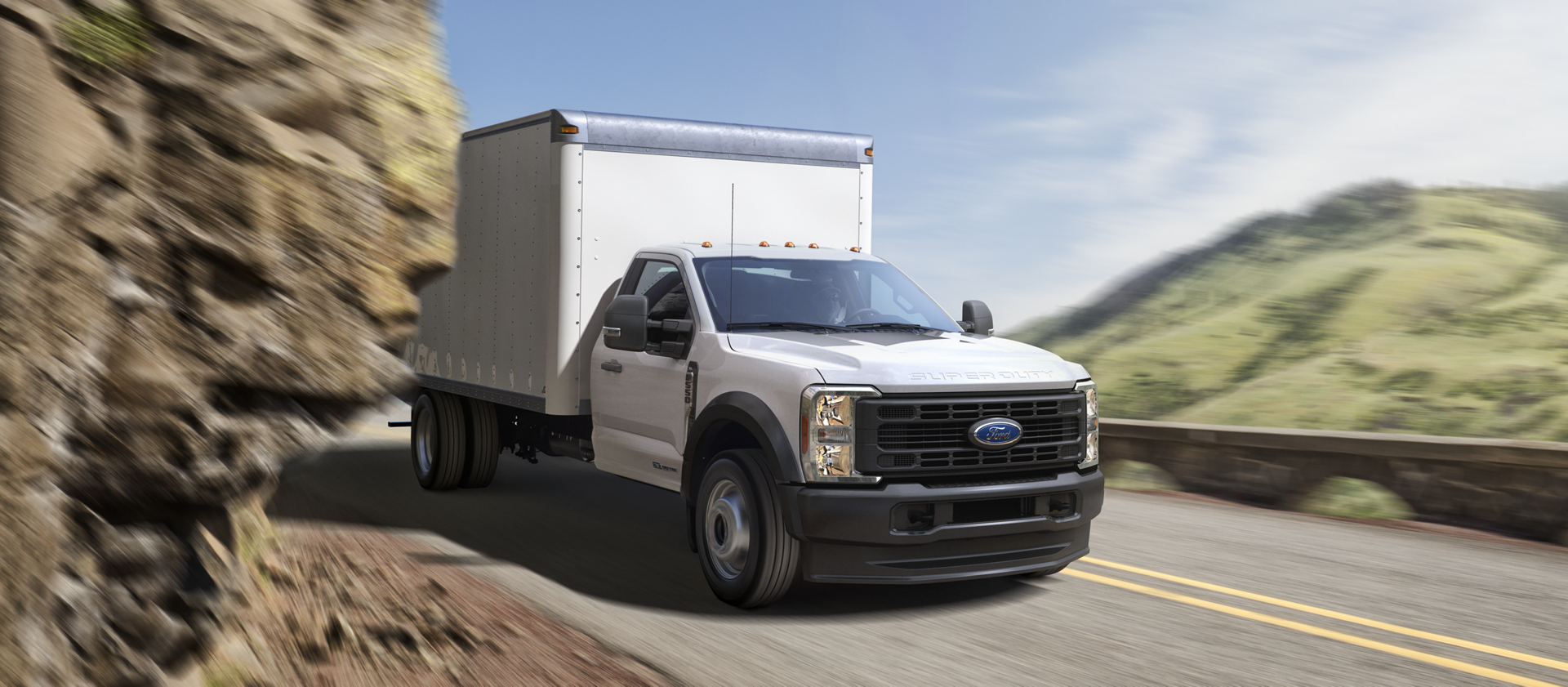 A 2026 Ford Super Duty® Chassis Cab with a box being driven through a tight mountain curve