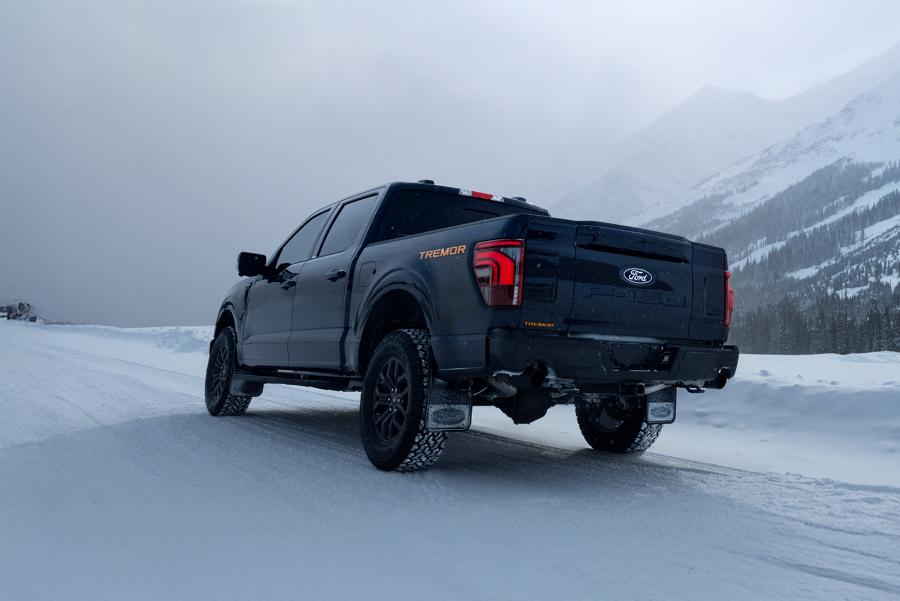 Rear view of an F-150 Tremor driving on a snow-covered mountain road.