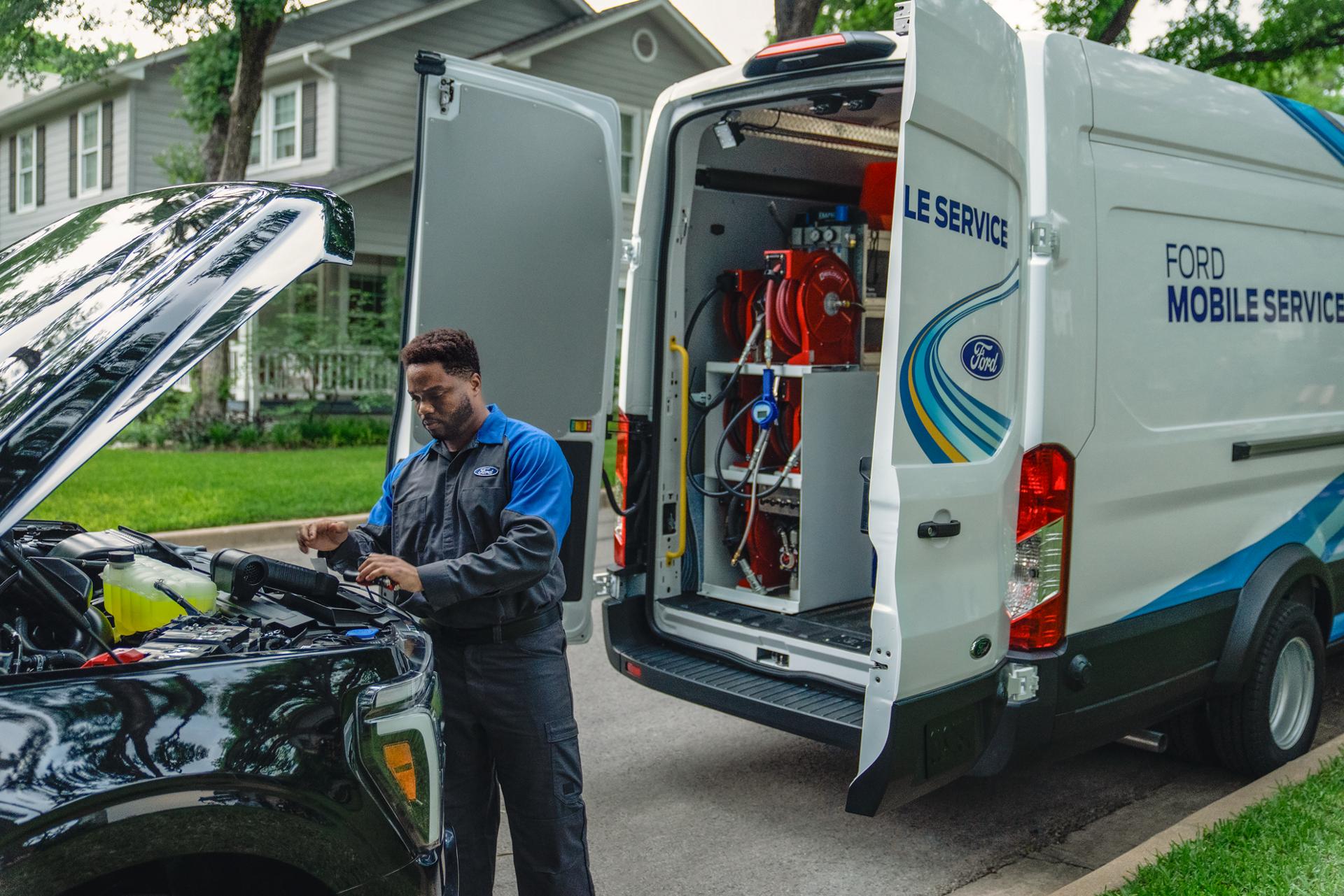 A Ford Service mobile technician works on a vehicle parked in a residential neighbourhood.