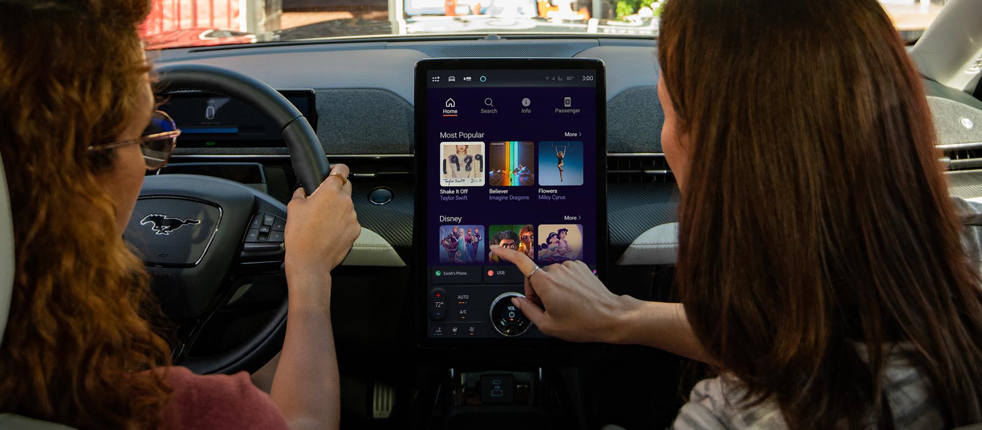 Two women in a 2026 Ford Mustang Mach-E® browsing karaoke options with available Connectivity Package