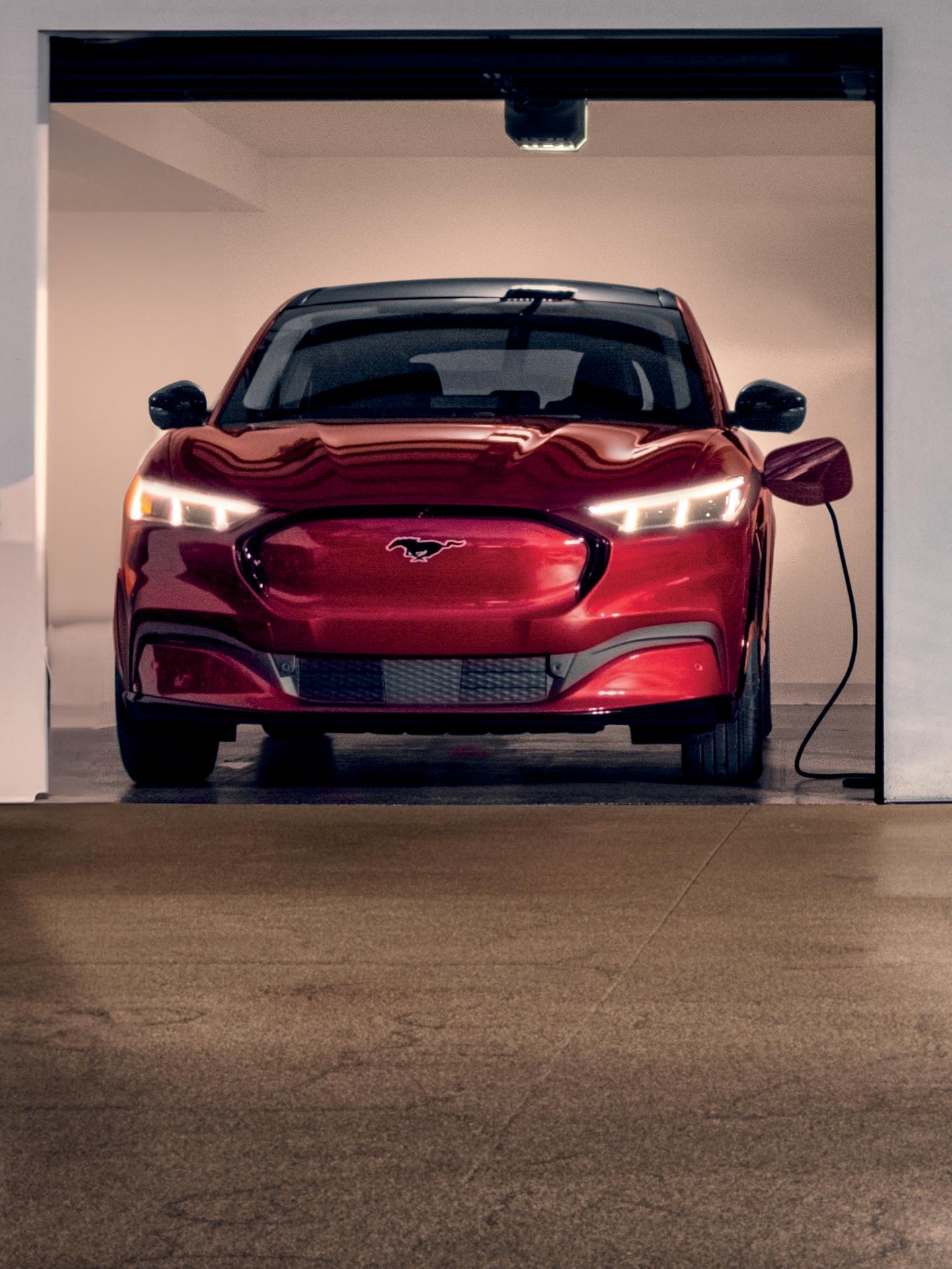 Mustang Mach-E parked and plugged into a charge station in a residential garage.