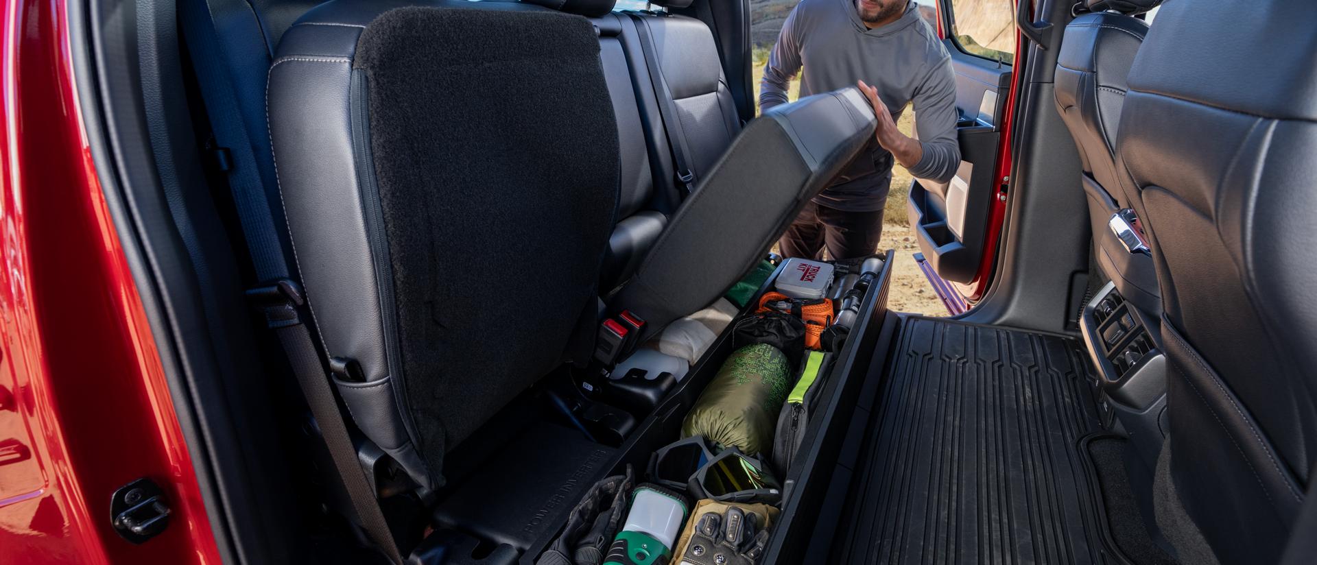 Person flipping up the rear seat showing the under-seat storage feature