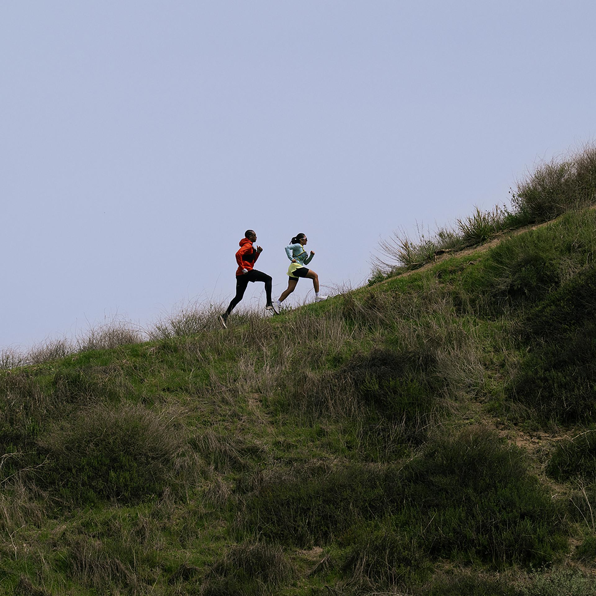 Two people seen from afar running up a hill