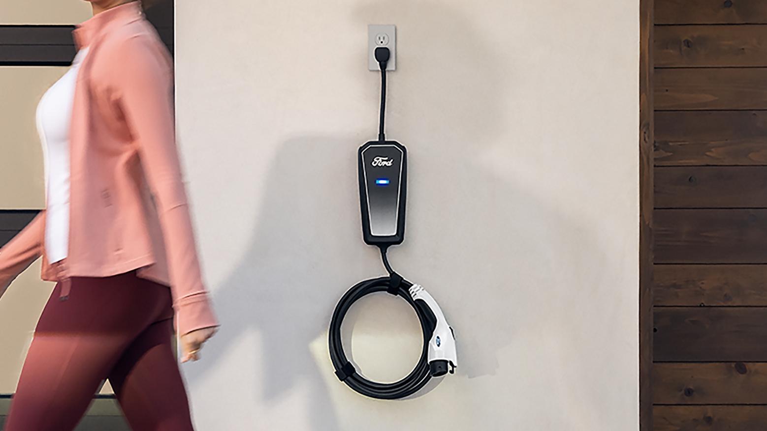 Woman walking by a Ford Mobile Power Cord installed on a wall