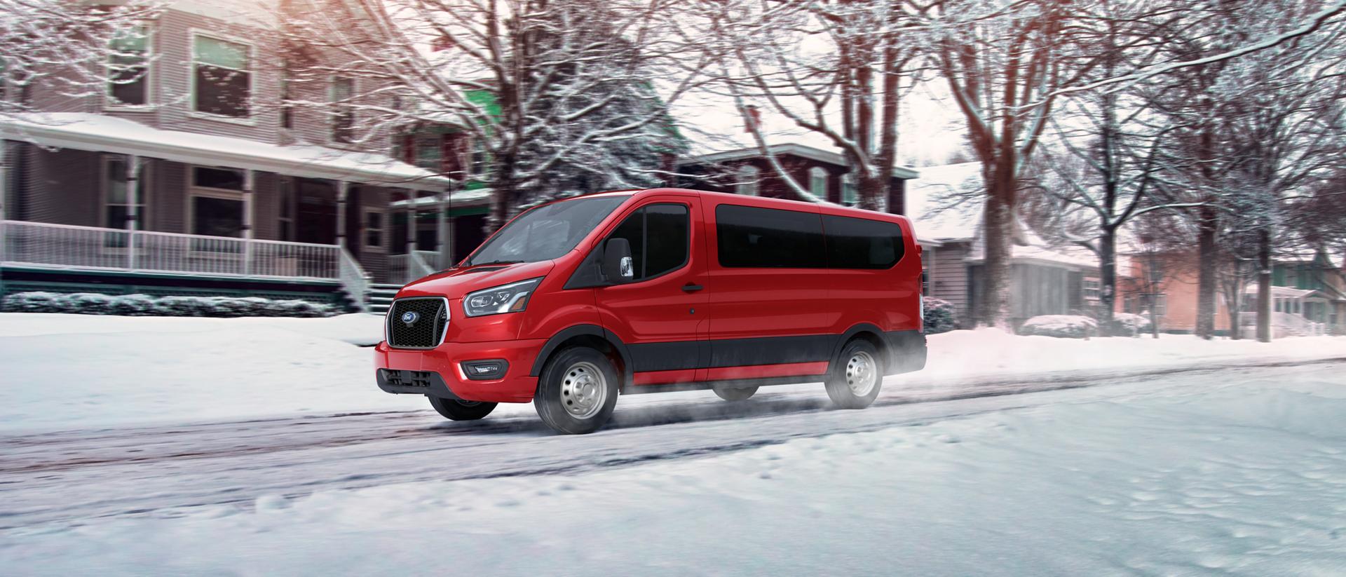 A 2025 Ford Transit® Van being driven down a neighbourhood street after snowfall
