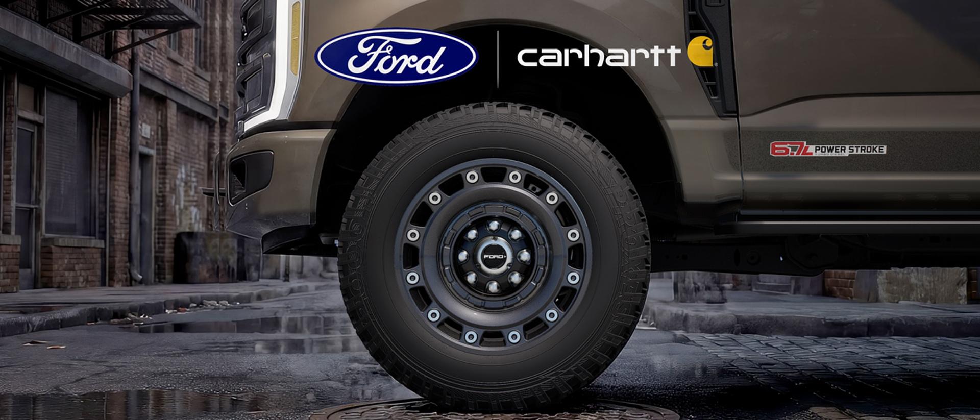 A close-up of a Ford Super Duty truck fender and large wheel, featuring the Ford and Carhartt logos.