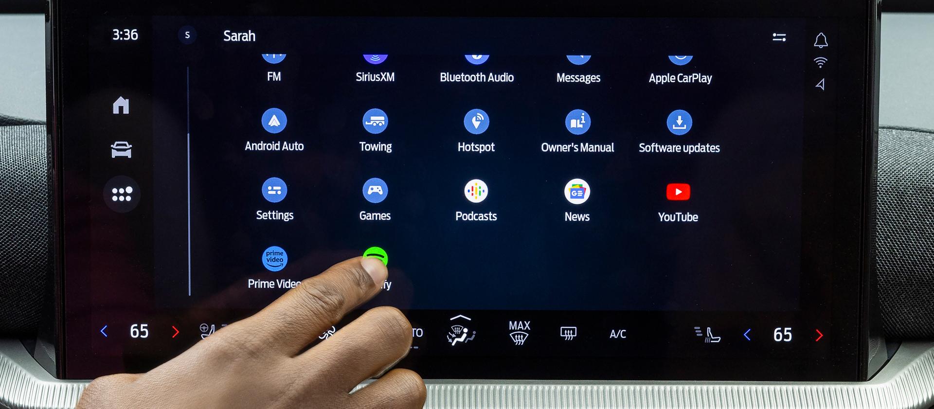 A driver's hand reaching out to touch an icon on the centre display of a 2026 Ford Explorer® SUV