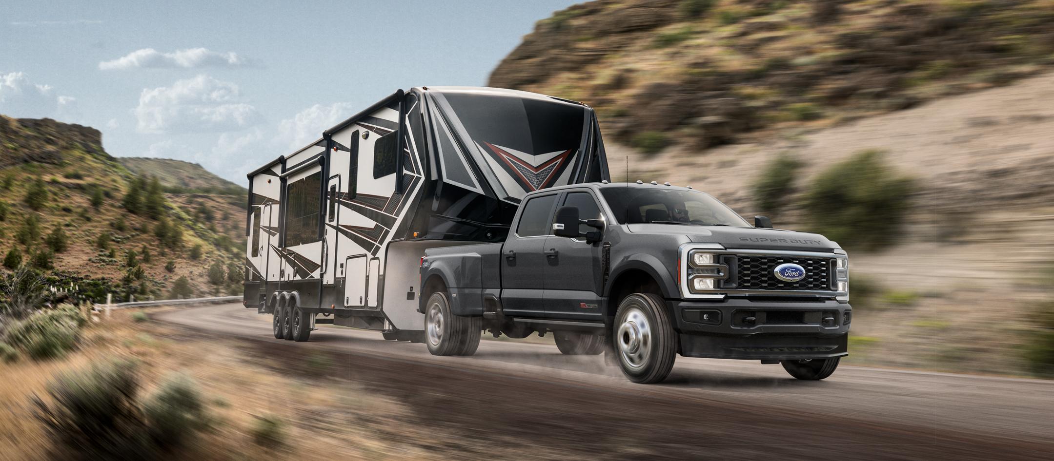 2026 Super Duty® F-450® Platinum® model in Carbonized Grey pulling a camper on a mountain road