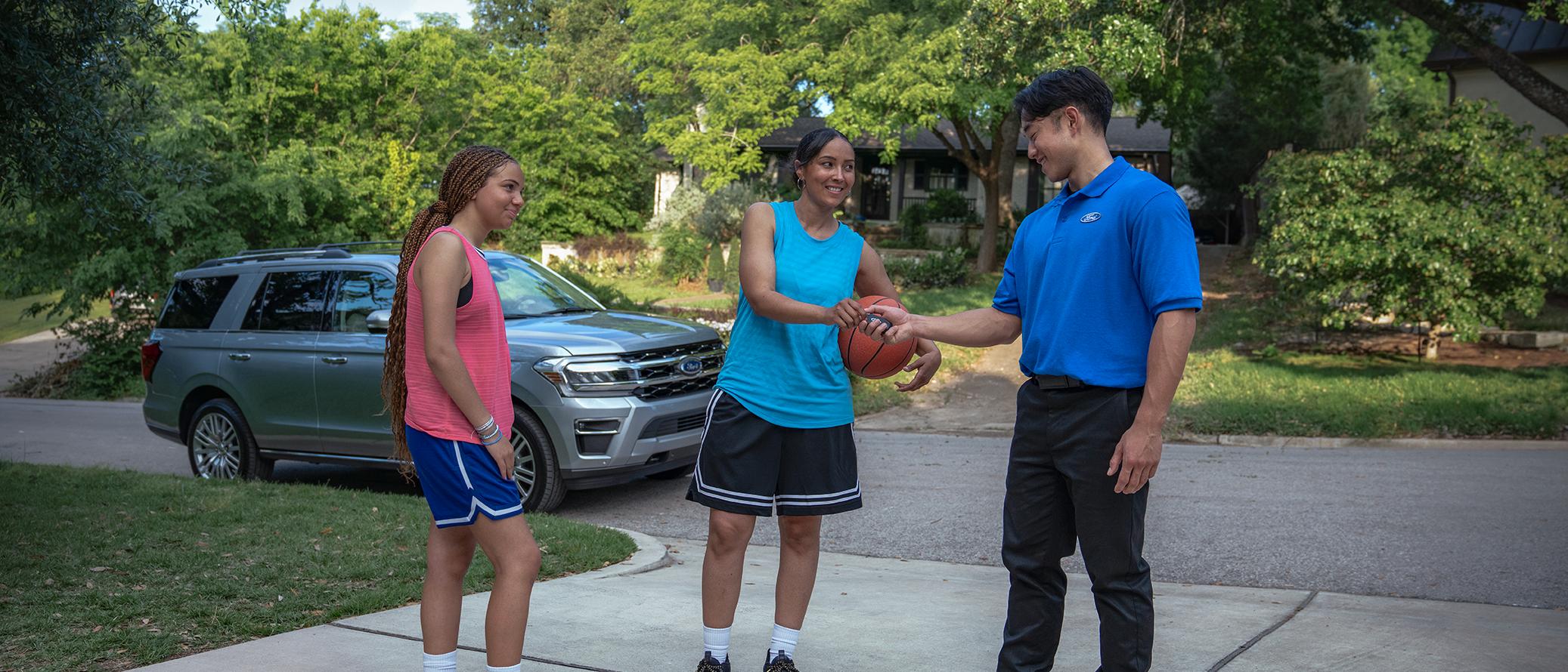 A Ford owner takes a break from playing basketball in the driveway to hand their keys to a Ford Service representative.