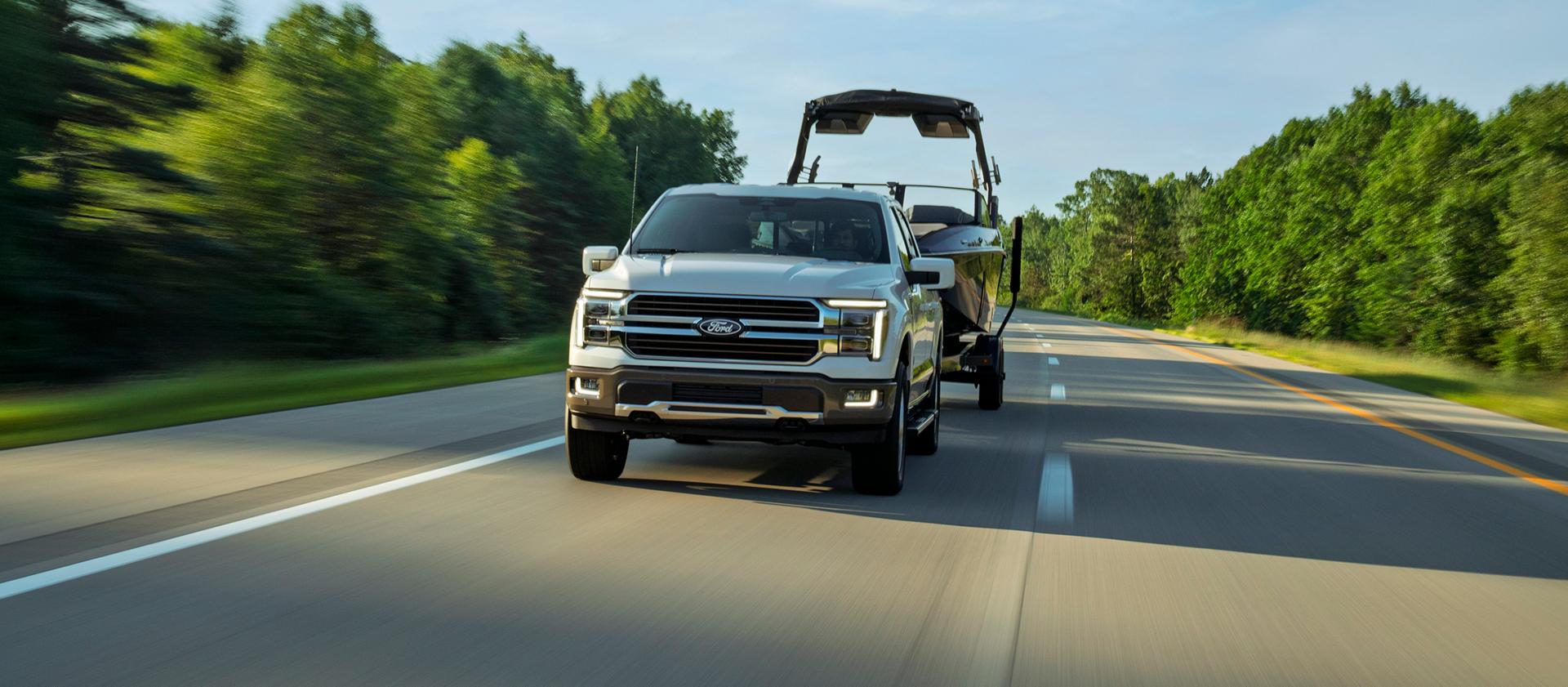 2027 Ford F-150® King Ranch® model pulling a boat on a two-lane road