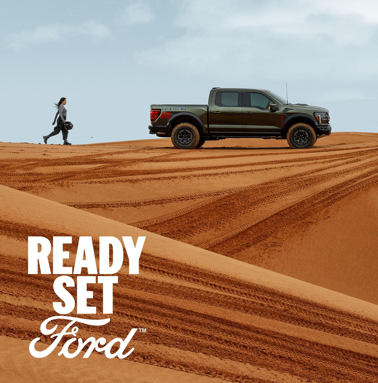 An F-150 in a desert landscape with Ready Set Ford Logo. 