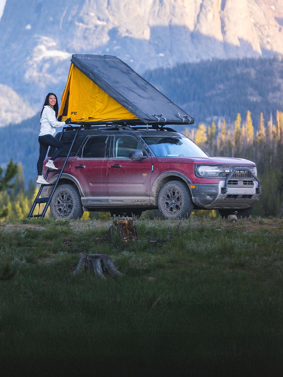 A red Bronco® Sport with roof tent accessory parked by a camp site.