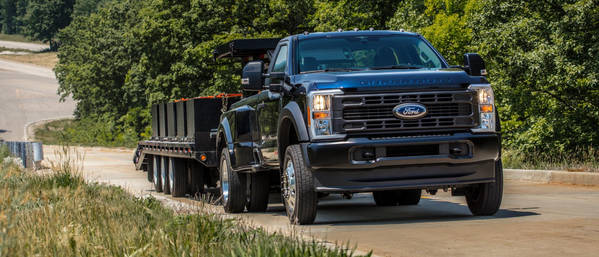2026 Ford Super Duty® pulling a large flat bed trailer up a paved hill
