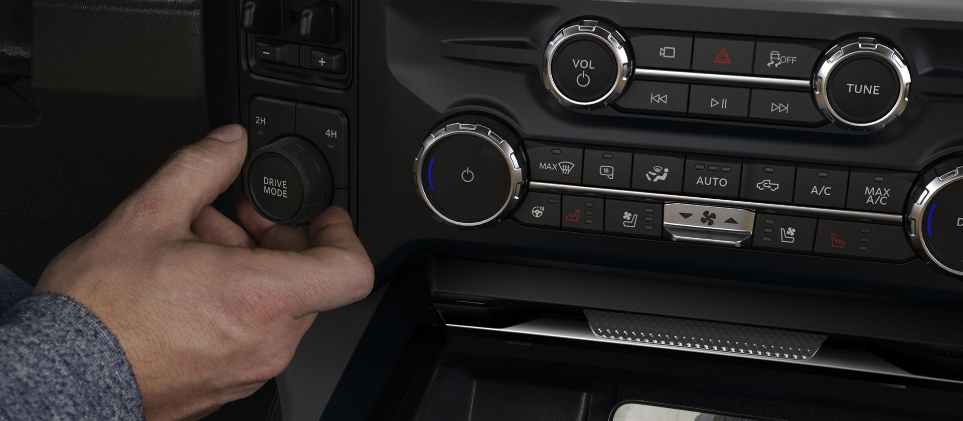 Adjusting the Drive Mode knob inside a 2026 Ford Super Duty®, while a phone charges with the wireless charging pad