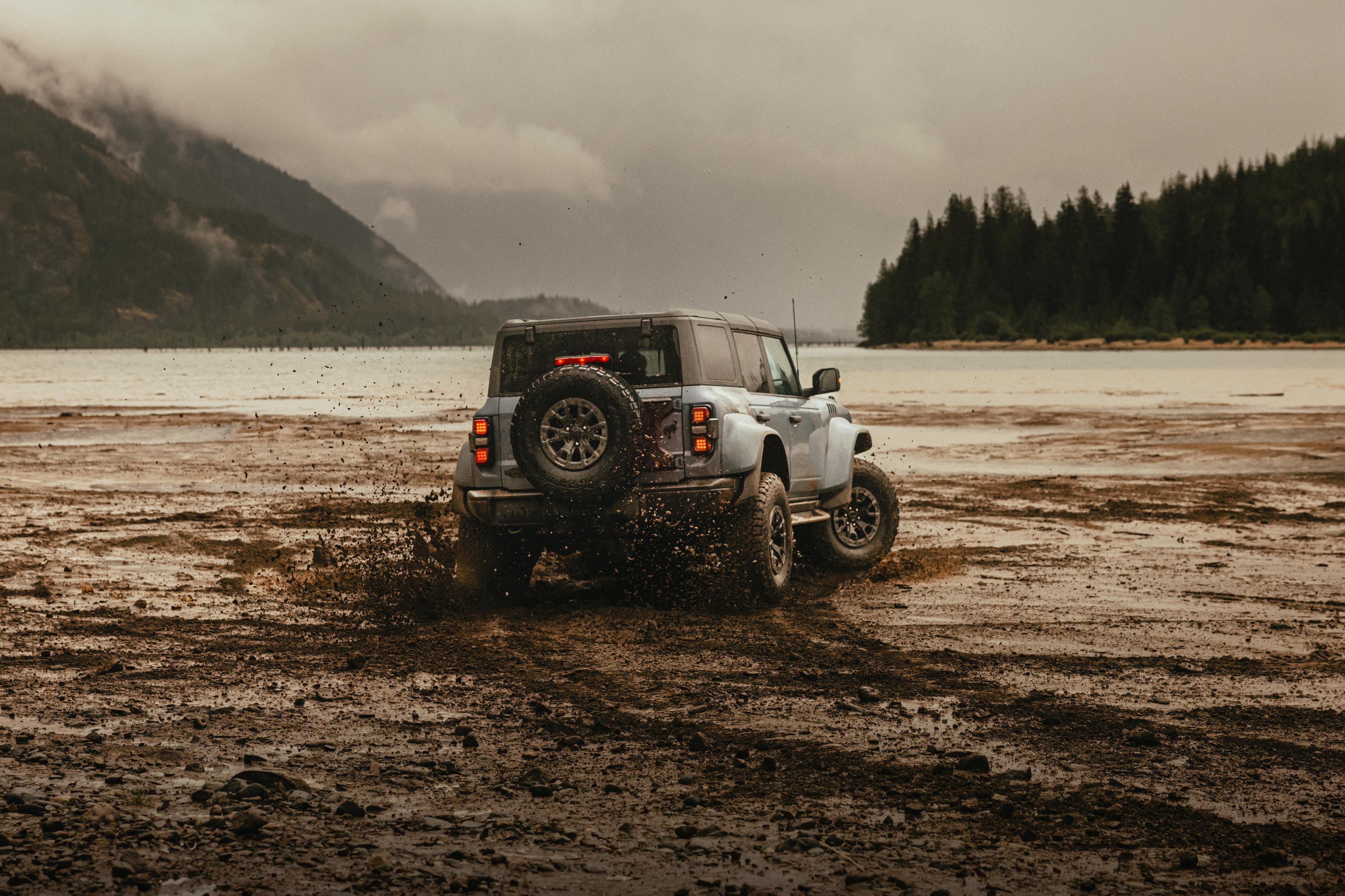 A 2025 Ford Bronco® Raptor® SUV driving on a mud flat in the rain