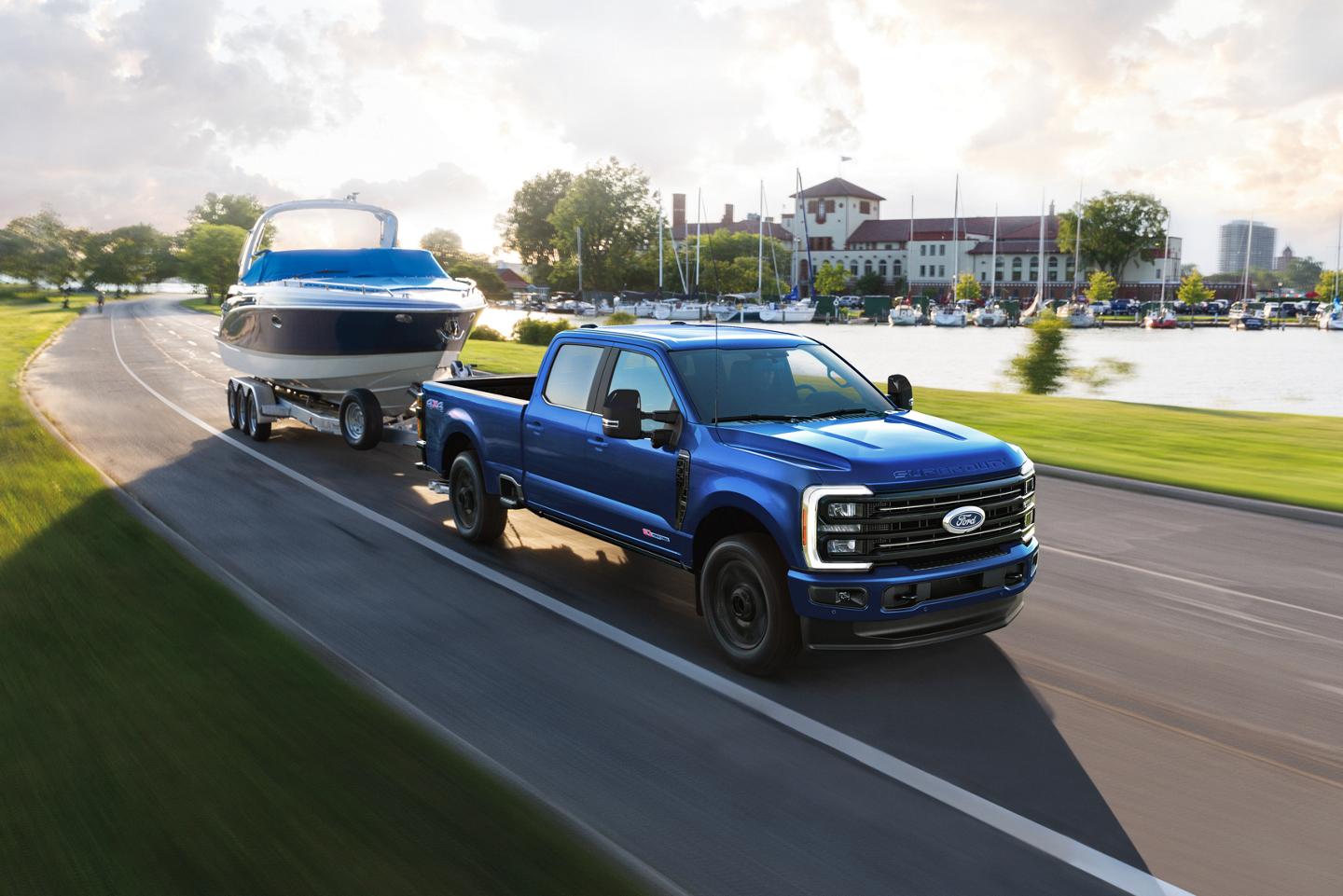 2027 Ford Super Duty® F-350® Lariat® model in Neptune Blue driving down a paved road while towing a speed boat