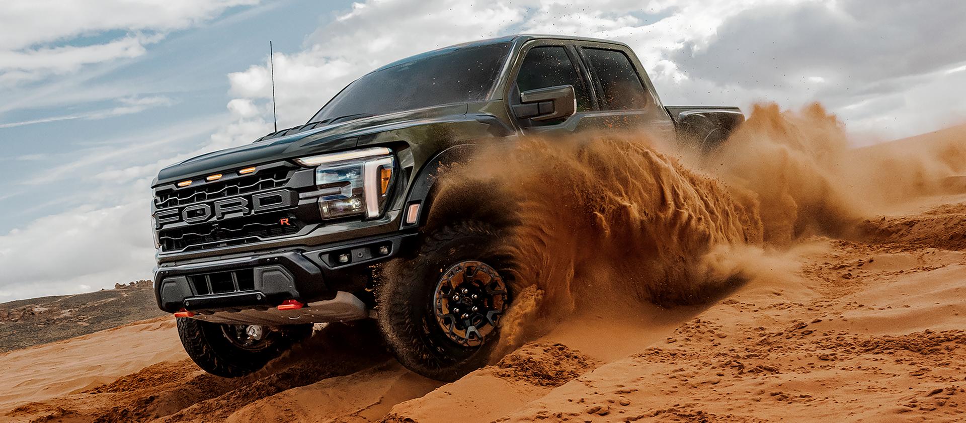 2026 Ford F-150® Raptor® pickup being driven in the desert kicking clouds of sand