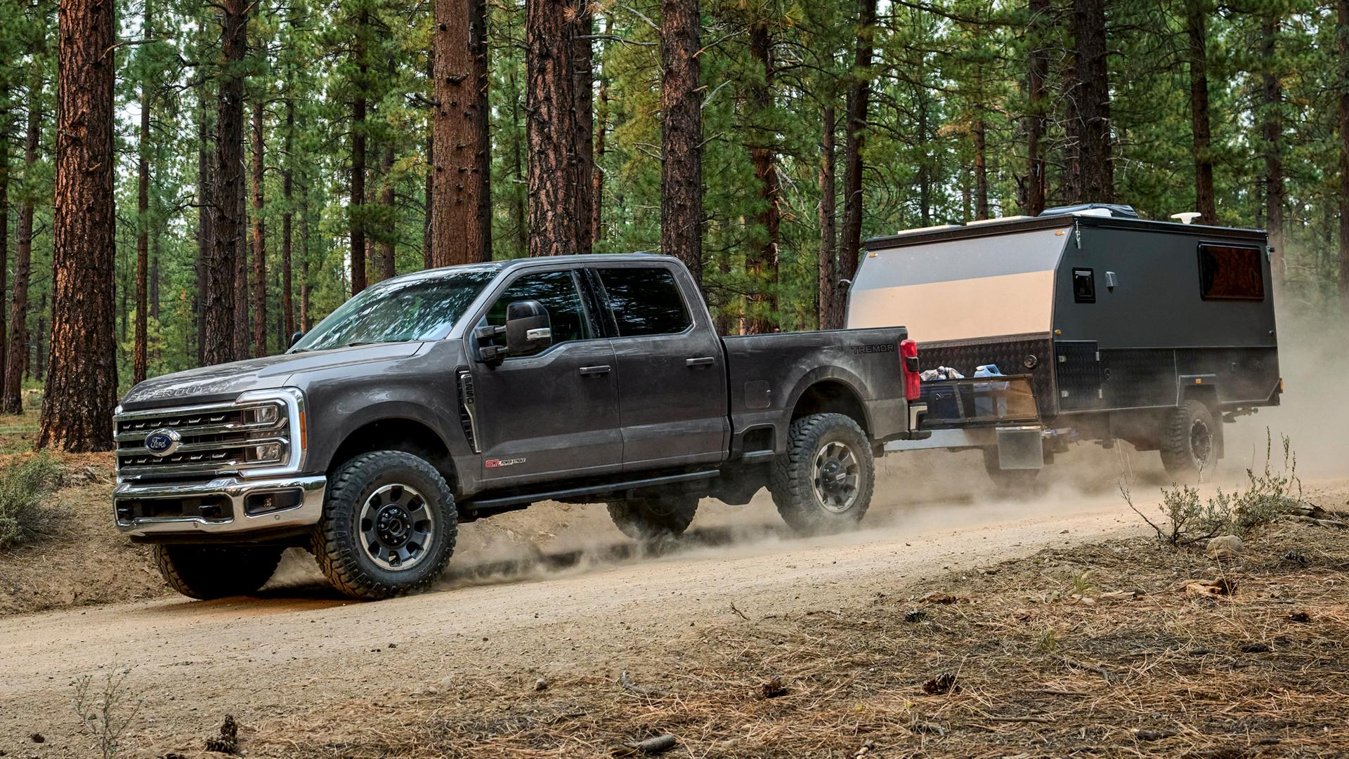 2026 Ford Super Duty® F-250® with the Tremor® Off-Road Package pulling a trailer on a dirt road in the woods